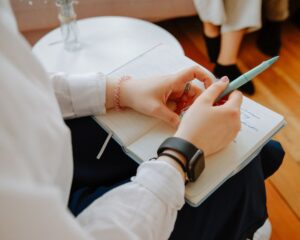 Nahaufnahme von Hand, die Notizen in ein Notizbuch schreibt