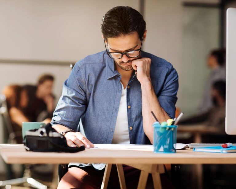 Junger Mann telefoniert und arbeitet gleichzeitig am Laptop