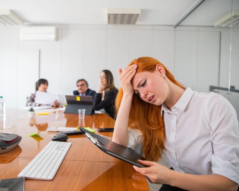 Gestresste Frau mit Tablet sitzt im Konferenzraum