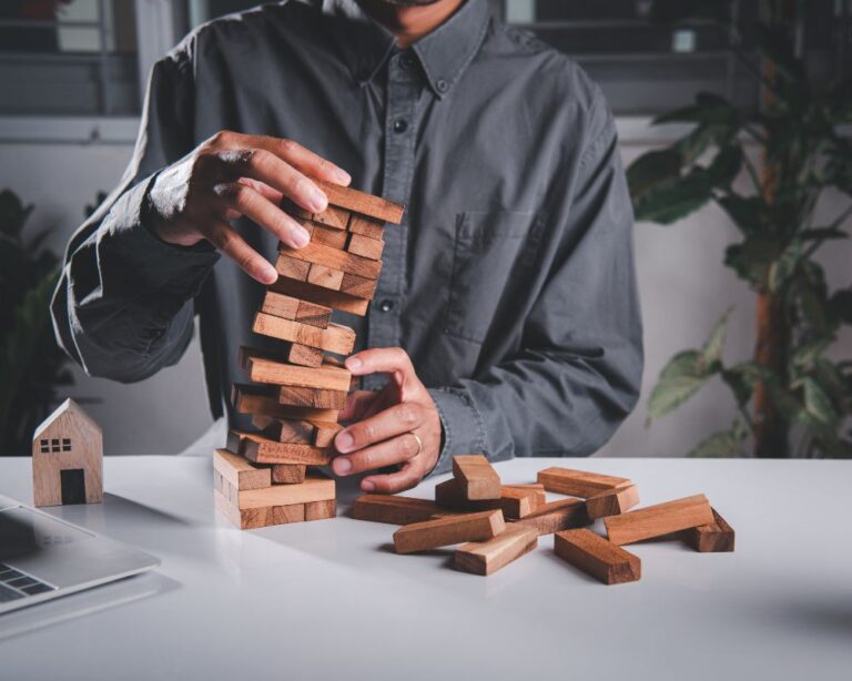 Hände mehrerer Personen bauen einen Jenga-Turm auf