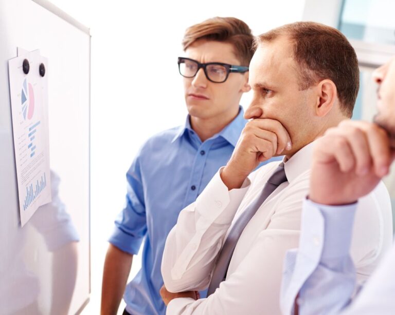 Zwei Geschäftsmänner analysieren etwas konzentriert auf einem Bildschirm