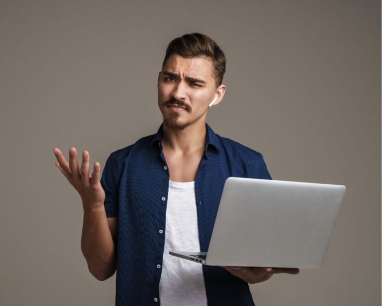 Mann mit fragender Geste hält einen Laptop in der Hand