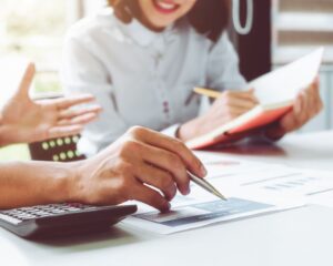 Hände mit Stift und Unterlagen in einer Beratungssituation