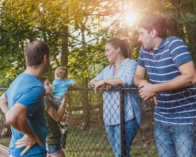 Zwei Familien unterhalten sich freundlich über einen Gartenzaun hinweg