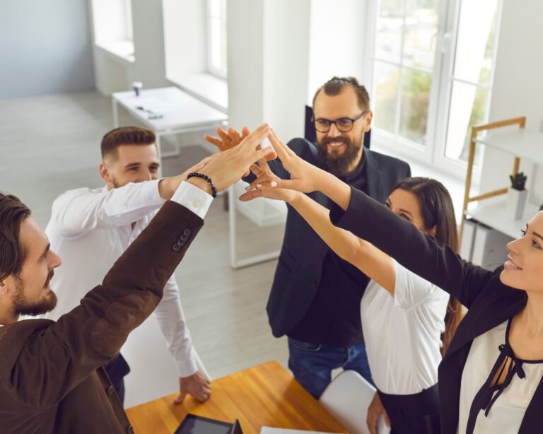 Kleines Team in Büroumgebung feiert mit gemeinsamer Geste