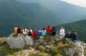 Gruppe sitzt auf einem Felsen und blickt ins Gebirge