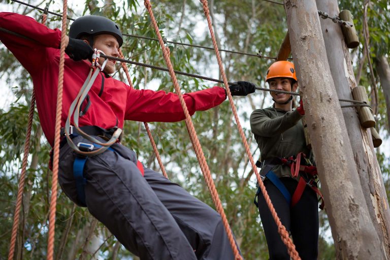 Zwei Personen sichern sich gegenseitig beim Klettern mit Seilen und Helm