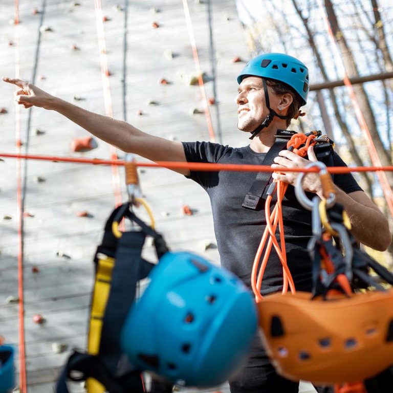 Mann mit Helm und Kletterausrüstung zeigt nach vorne