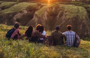 Gruppe sitzt beim Sonnenuntergang auf einer Anhöhe